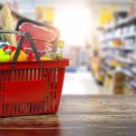 ID Uproar Erupts Over NYC Grocery Plan Red shopping basket filled with groceries on a store aisle