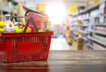 ID Uproar Erupts Over NYC Grocery Plan Red shopping basket filled with groceries on a store aisle