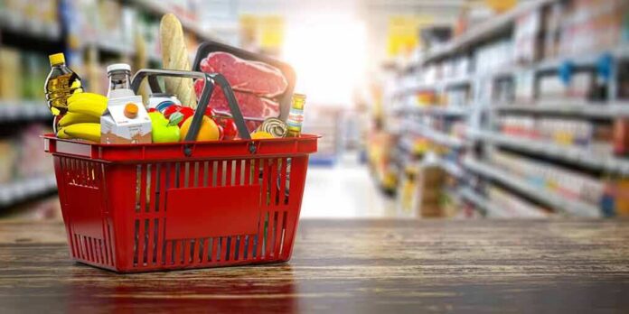 shutterstock_1696083520 Red shopping basket filled with groceries on a store aisle