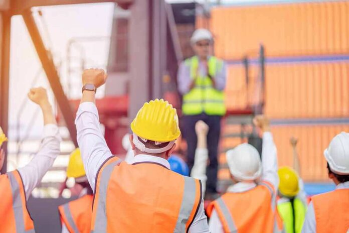 shutterstock_1919760773-1 construction workers raising fists during a safety briefing