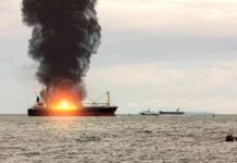 Cargo Ship Downed — Who Pulled Trigger? Cargo ship on fire with thick black smoke at sea
