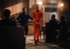 New Mexico Justice Runs On Deals Inmate in orange jumpsuit escorted by officer in courtroom