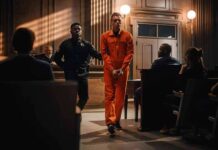 New Mexico Justice Runs On Deals Inmate in orange jumpsuit escorted by officer in courtroom