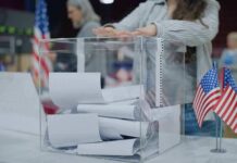 Person casting a ballot into a clear box at a polling station