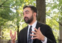 Man in a suit gesturing while speaking outdoors