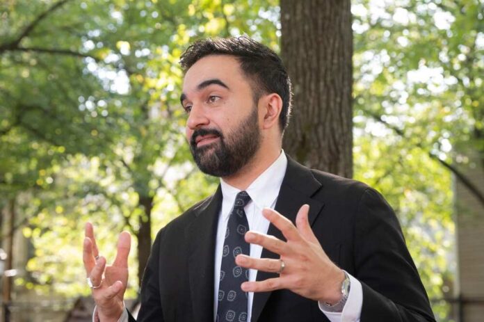 Mayoral,Candidate,Zohran,Mamdani,Attends,Canvassing,Ahead,Of,Vote,In Man in a suit gesturing while speaking outdoors