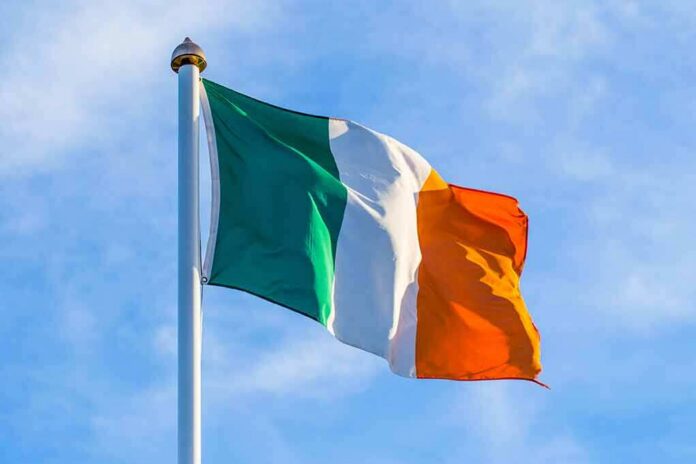 shutterstock_506850232 Irish flag on a flagpole against a blue sky