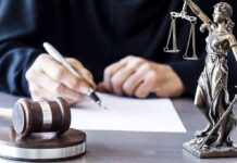 Judge Slams Red Flag Overreach On Kids Judge writing at desk with gavel and Lady Justice statue