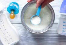 Baby formula powder in a can with a blue scoop