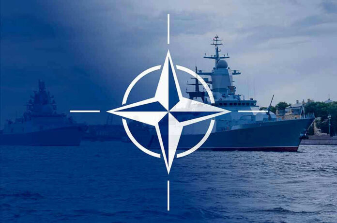 2113634360 NATO emblem overlaying naval ships in the ocean.