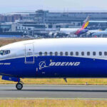 Trade War Turbulence Hits Flyers Boeing 737-800 on airport runway with other planes.