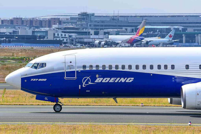 2406303801 Boeing 737-800 on airport runway with other planes.