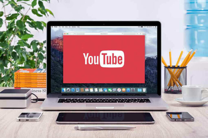 293731811 YouTube logo on a laptop screen on desk.