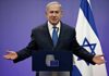 man in suit speaking at a podium with Israeli flag