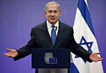 UN Showdown: Netanyahu Taunts City Hall man in suit speaking at a podium with Israeli flag