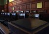Backlash Forces Juror Underground Empty wooden jury box with numbered chairs