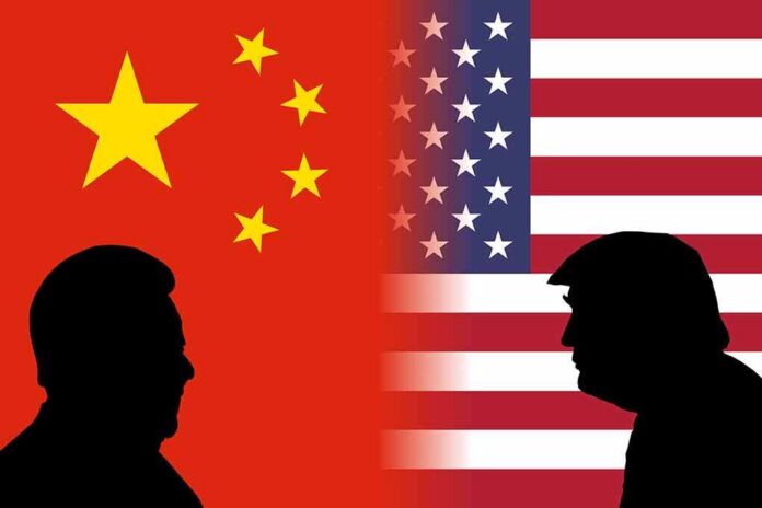 shutterstock_1158237289 Silhouetted leaders facing off before China and United States flags