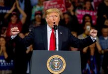 Rare GOP Rebuke Hits Trump’s Immigration Push Donald Trump speaking at a rally podium with arms raised