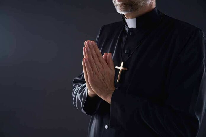 shutterstock_1212427192 Clergyman in black robe praying with hands together