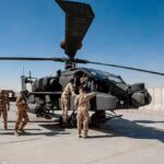 Billion-Dollar Laser Bet Sparks Pentagon Uproar Soldiers inspect a military attack helicopter on a tarmac