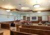Tate Brothers Entangled In Disturbing Romania Case Empty courtroom with wooden benches and judge's bench