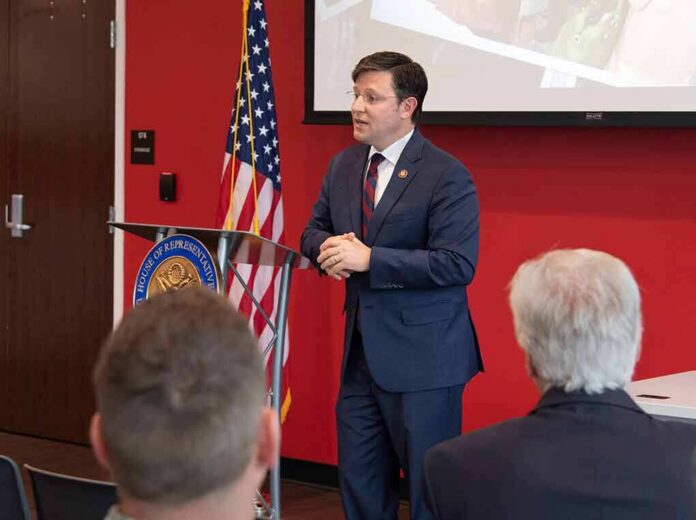 shutterstock_1381036310 Speaker in a navy suit addressing an audience at a podium