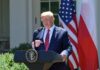 White House Theater Masks High-Stakes Moves Donald Trump speaking at a podium with U.S. and Polish flags behind him