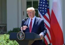 White House Theater Masks High-Stakes Moves Donald Trump speaking at a podium with U.S. and Polish flags behind him