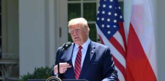 Donald Trump speaking at a podium with U.S. and Polish flags behind him