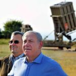 Ehud Barak and another man outdoors near a missile defense battery