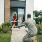 Commission Craze Hits Military Families soldier kneeling to embrace daughter on home walkway