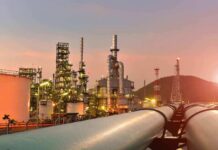 Backdoor Oil Route Shocks The Gulf Oil refinery with pipelines at sunset