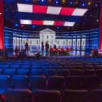 Clip War Erupts: Raskin Interview Twisted Debate stage with red and blue lighting and empty audience seats