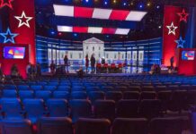 Clip War Erupts: Raskin Interview Twisted Debate stage with red and blue lighting and empty audience seats