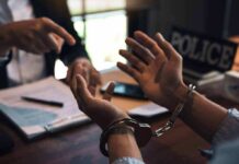 Berlin-Vienna Plot Exposed – Chilling Handcuffed person talking with an officer at a desk