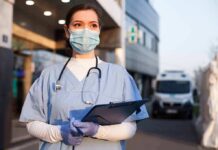 ER Chaos Sparks Miami Outrage Healthcare worker in scrubs wearing mask and gloves holding a clipboard