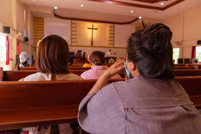 shutterstock_1773600770 people seated in church pews facing a cross