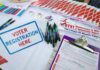 Voter registration table with forms, pens, and informational materials