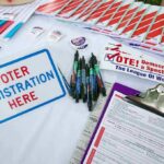 Netflix Tycoon Targets Voter ID Voter registration table with forms, pens, and informational materials