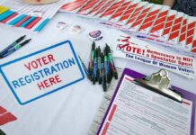 Netflix Tycoon Targets Voter ID Voter registration table with forms, pens, and informational materials