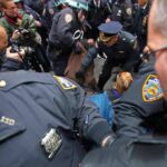 Cardiac Chaos At NYPD Event Police officers detain a person amid a crowded street scene