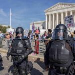Pastor’s Bombshell Sparks Mass Arrests Riot police stand in front of a courthouse during a protest