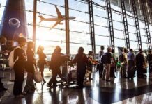 Passengers queue inside an airport terminal at sunset
