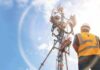 U.S. Loan Supercharges Africa Network Fight Telecom tower with worker in safety vest under bright sky