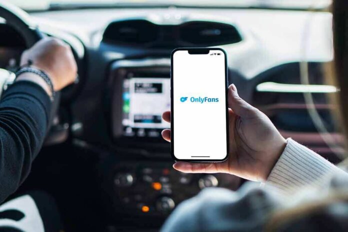 shutterstock_2211645831 Person holding smartphone with OnlyFans app open in a car