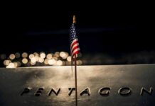Small American flag on a memorial with bokeh lights at night