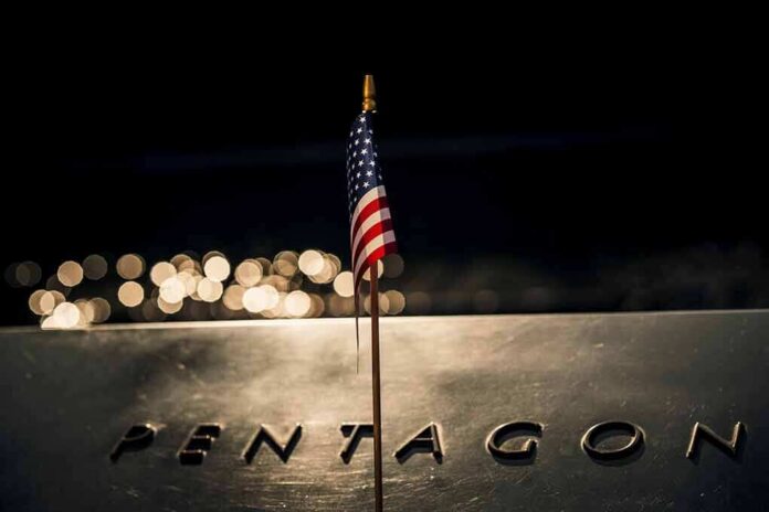 shutterstock_2321355077 Small American flag on a memorial with bokeh lights at night