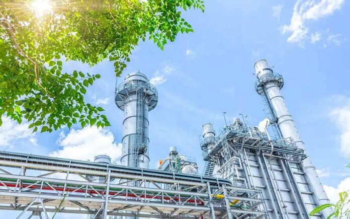 shutterstock_2349413829 Industrial power plant with tall chimneys under blue sky