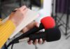 Billionaire Blitz Upends UK Politics Journalist holding two microphones while writing in a notebook