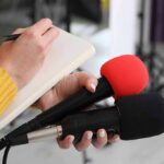 Trump’s Bold Foster Push Stuns D.C. Journalist holding two microphones while writing in a notebook